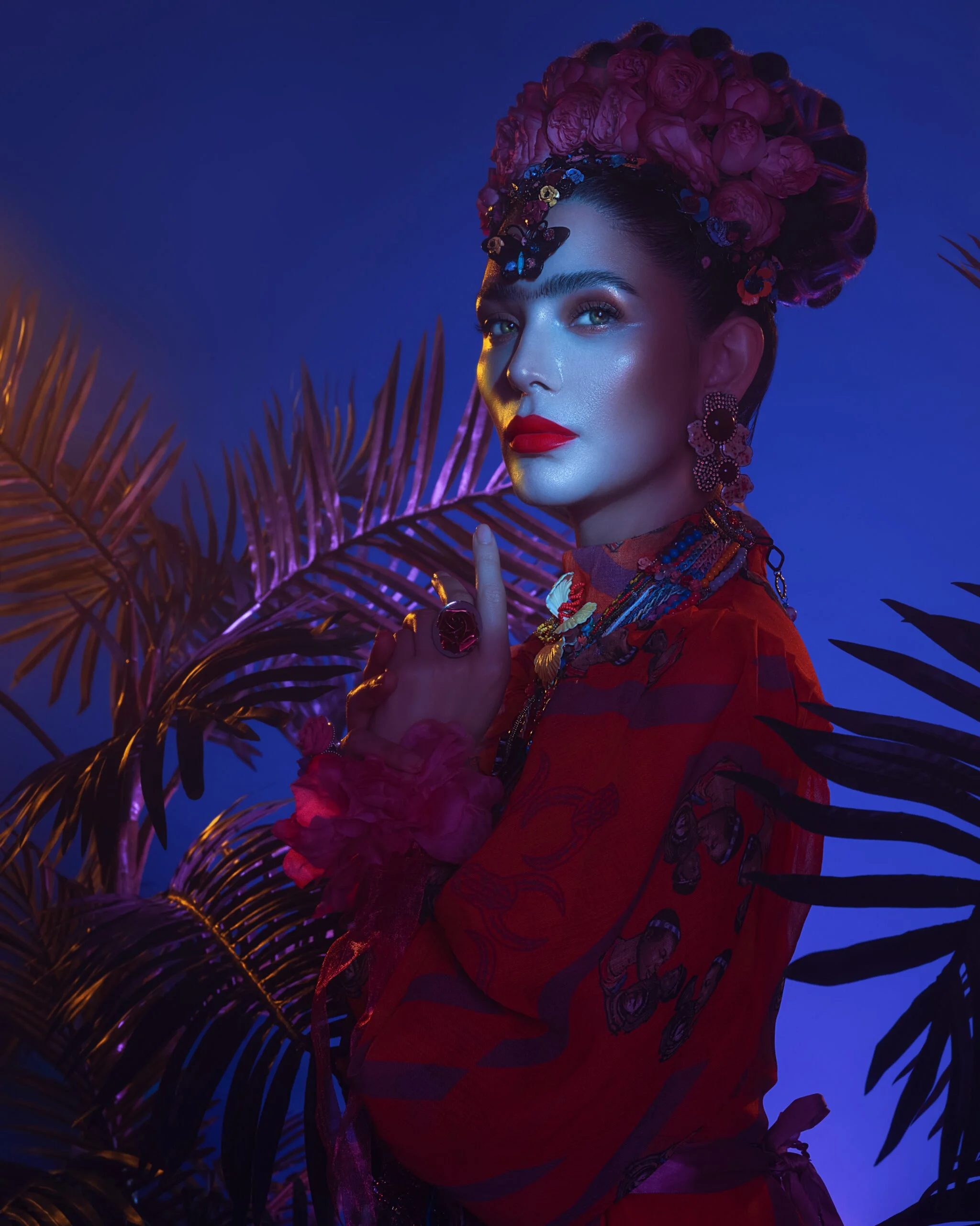 Portrait of a woman styled after Frida Kahlo, framed by natural foliage