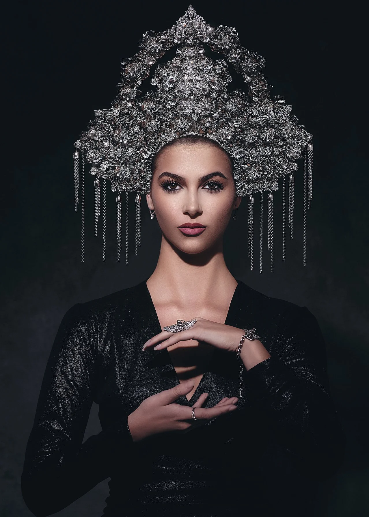Dramatic portrait of a woman wearing an ornate crystal crown with chandelier detailing