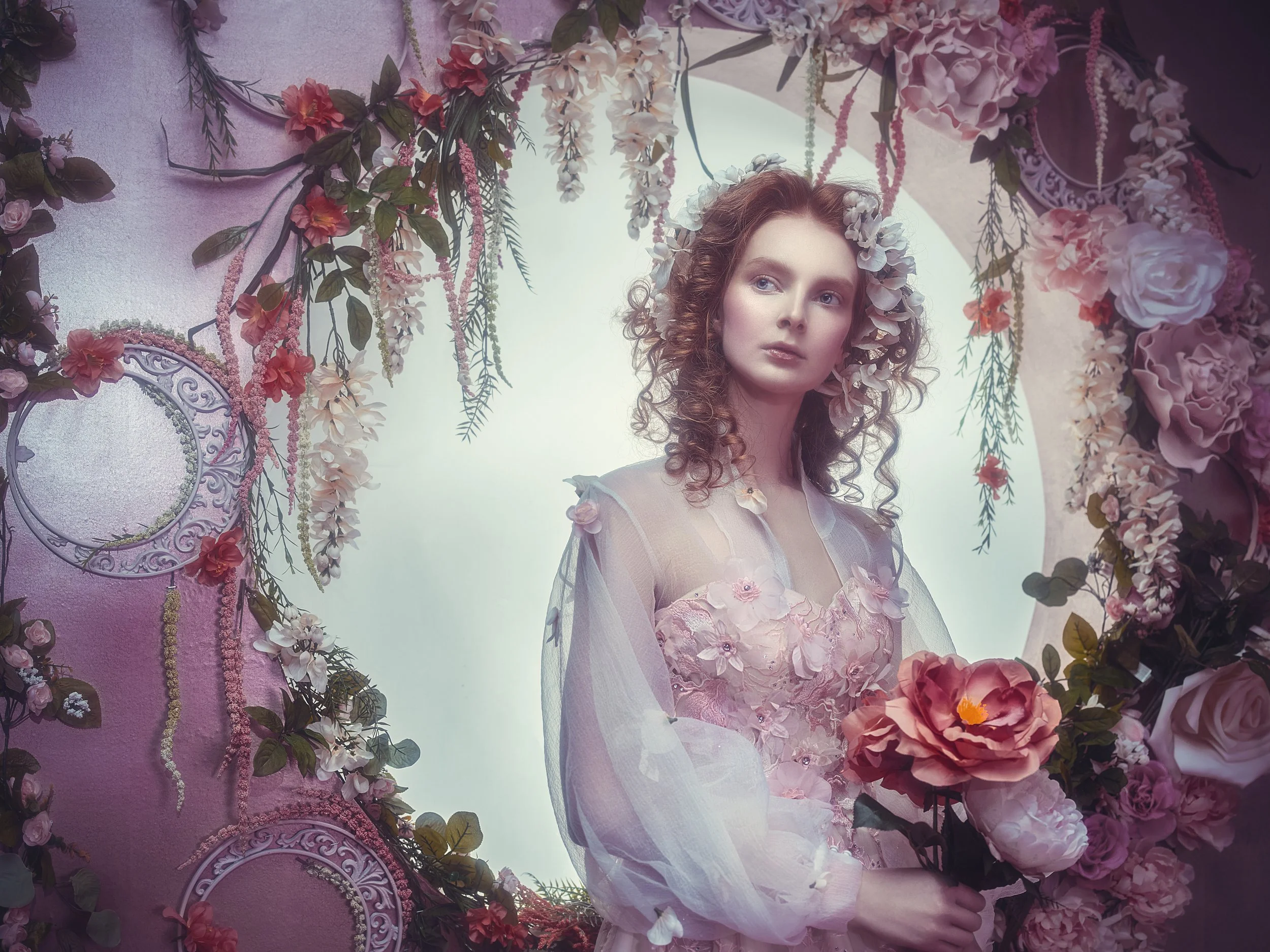 Fine art portrait of a woman surrounded by flowers in a soft dreamlike setting