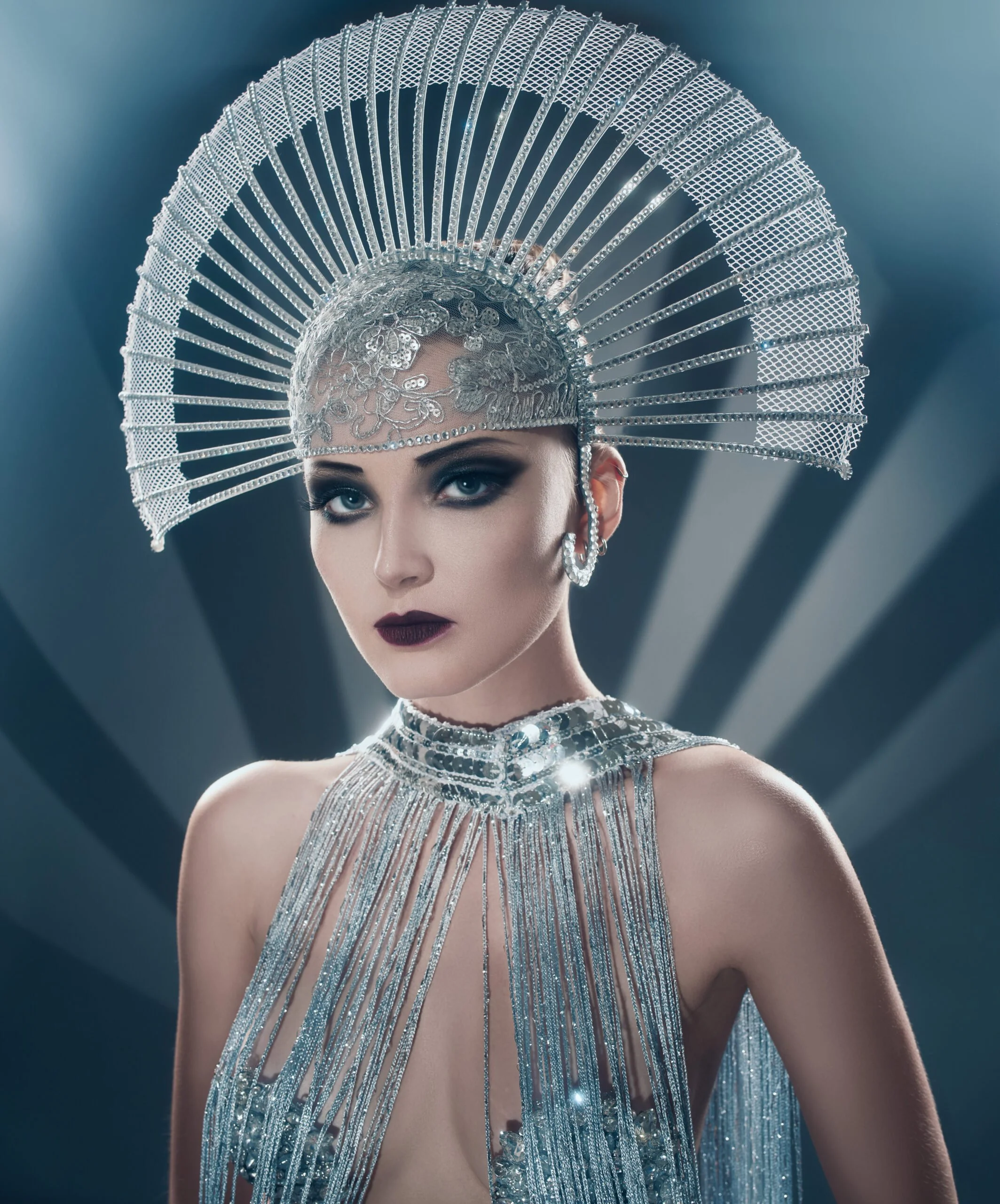 Art deco inspired portrait of a woman in a silver fan headdress and beaded costume