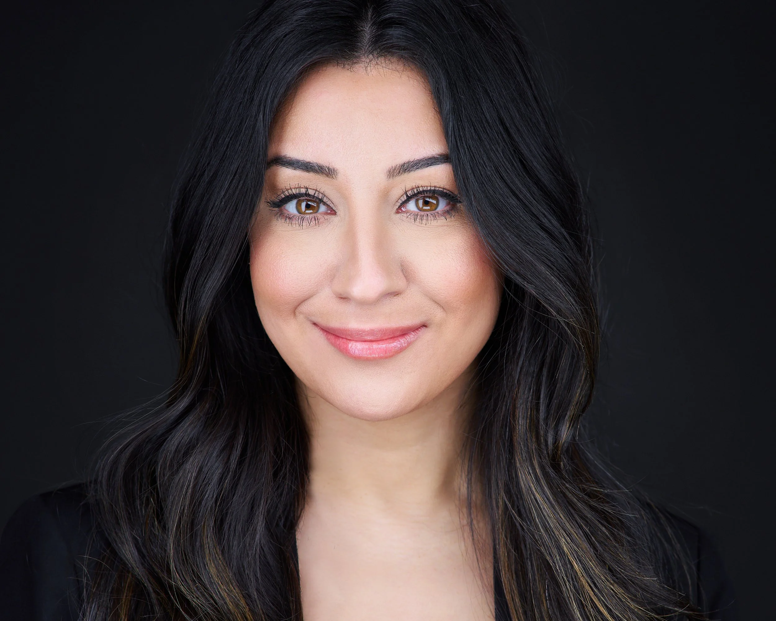 LinkedIn headshot of a professional woman in a dark blazer, photographed on a dark background at the West Bloomfield studio