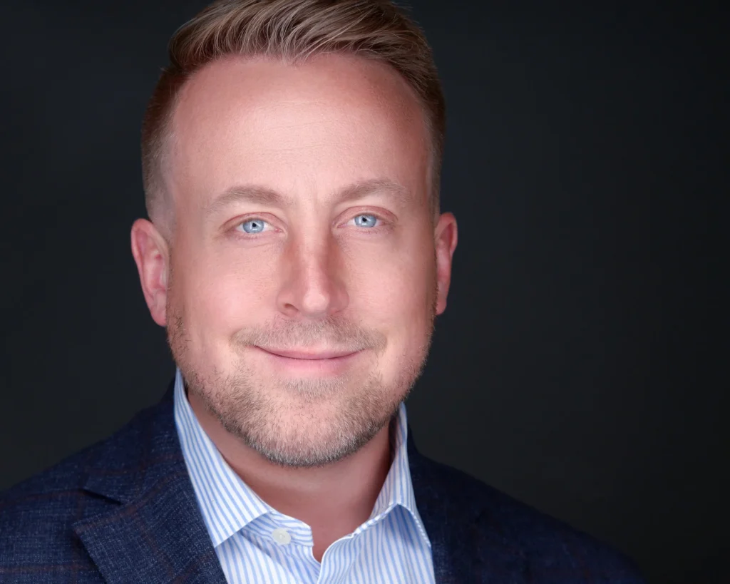 Executive headshot of a man in a suit and tie, studio lit